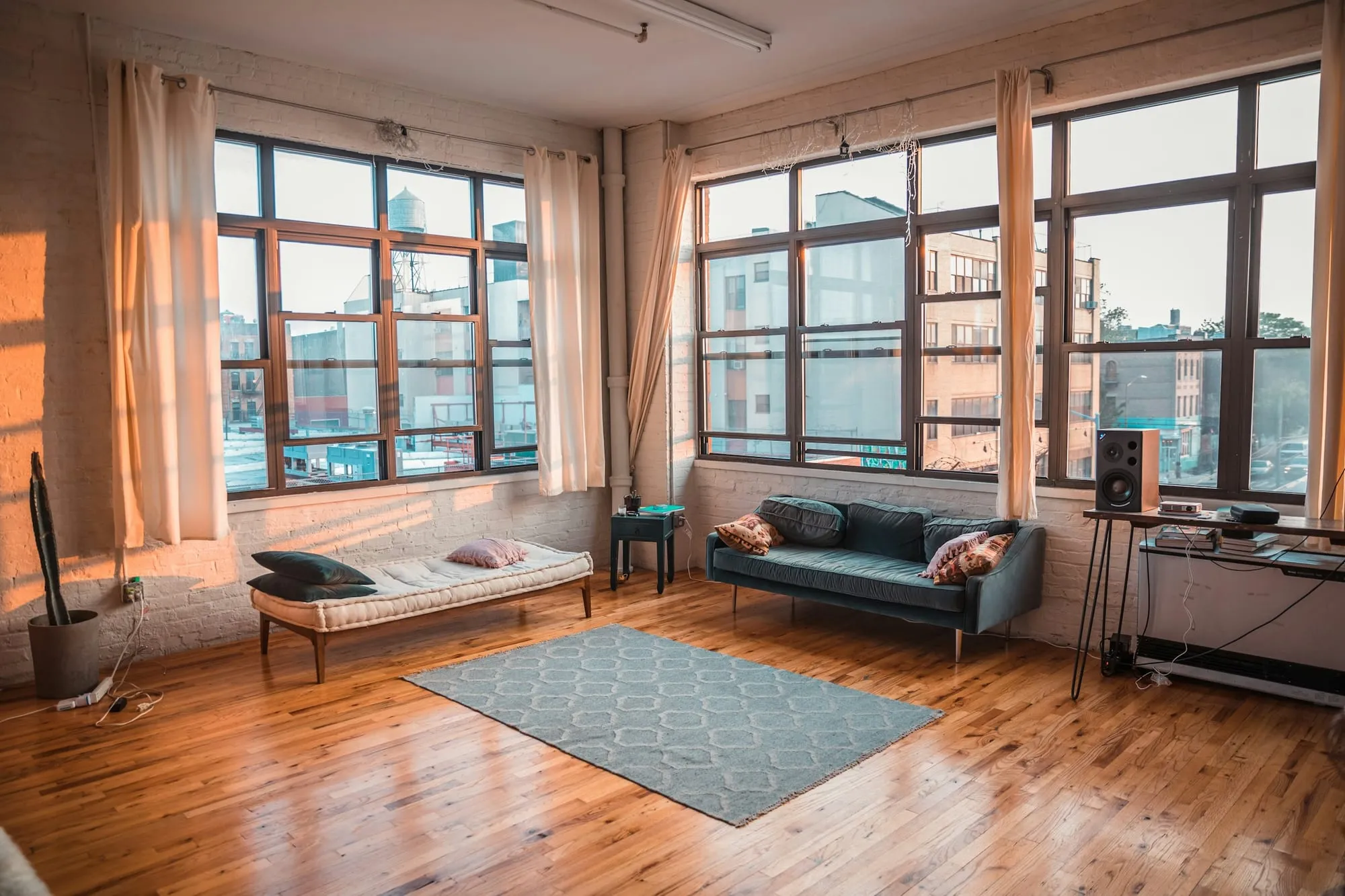 Wohnzimmer mit hohen Sprossenfenstern, Dielenboden und Sofa im Abendlicht
