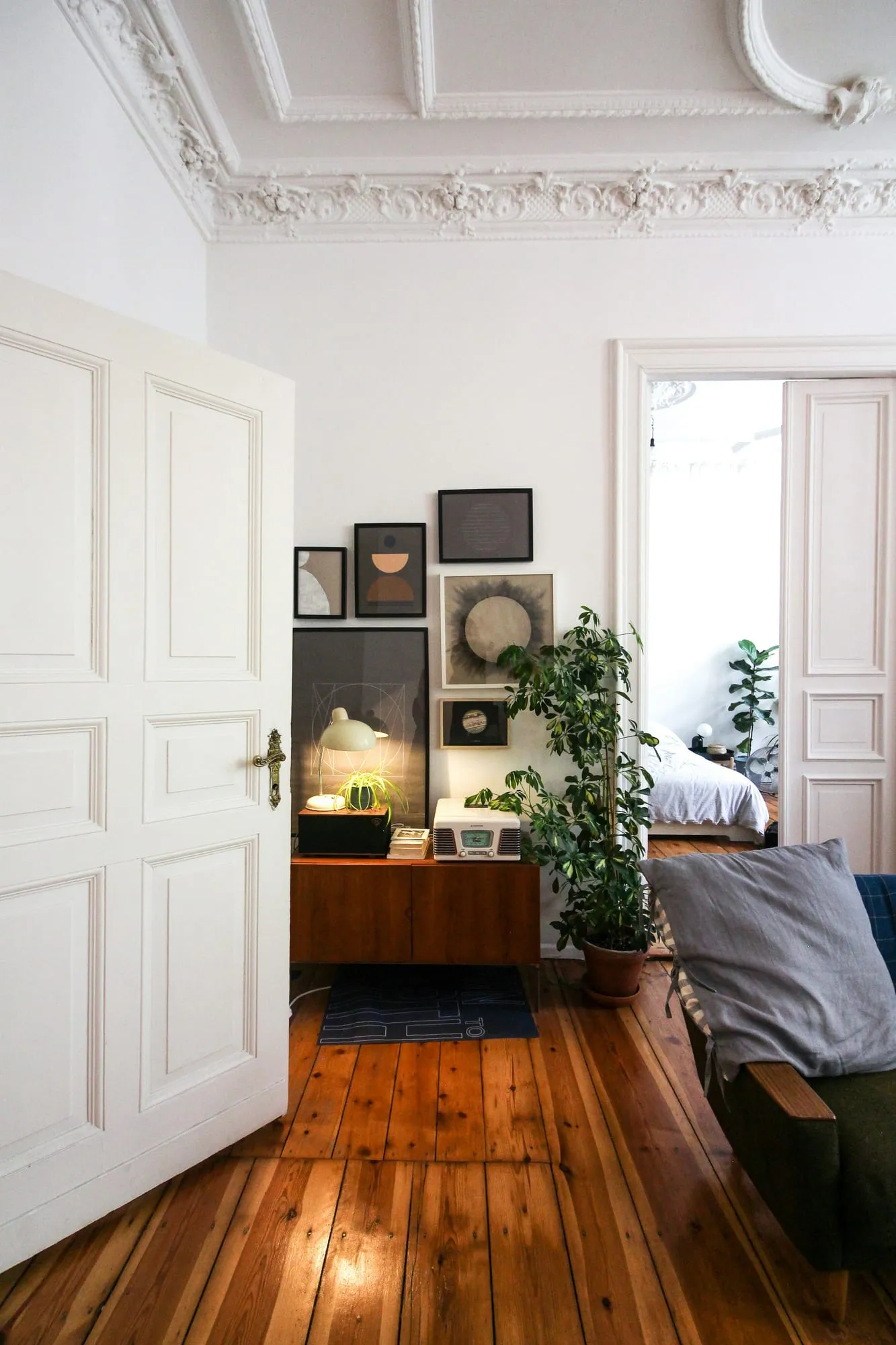 Weiße Kassettentür mit Stuck an der Decke und Dielenboden im Altbau
